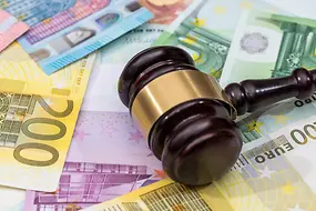 Ein Richterhammer liegt auf verschiedenen Euro-Scheinen